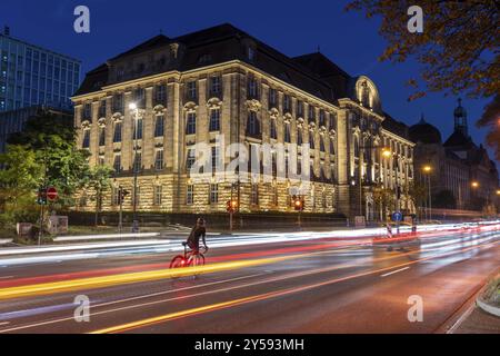 Abendlicher Stadtverkehr, Cecilienallee, Bundesstraße B1, Radfahrer wartet in einer Linksabbiegespur, um seine Reise fortzusetzen, Gebäude des Düsseldorfer Stadtzentrums Stockfoto