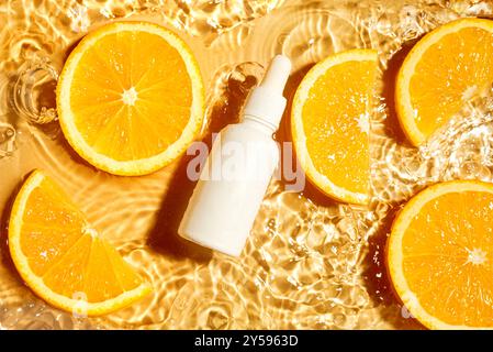 Tropfflasche ohne Branding mit Schönheitsserum oder ätherischem Öl und Orangen-Zitrusscheiben im Hintergrund mit Spritzwasser, Draufsicht. Feuchtigkeitsspendende organische VI Stockfoto