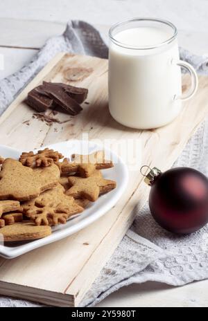 Schließen Sie mit der traditionellen Lebkuchen Cookies auf einen Teller und eine Tasse Milch auf einem Holzbrett auf einem Küchenpapier Stockfoto