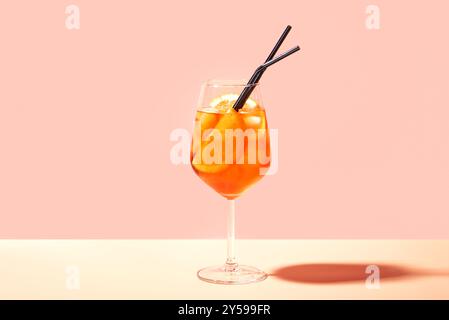 Aperol Spritz Cocktail im Glas mit orangefarbenen Scheiben auf rosa pfirsichfarbenem Hintergrund, Kopierraum, trendiges hartes Licht. Köstliches Sommergetränk Aperol Spritz Aper Stockfoto