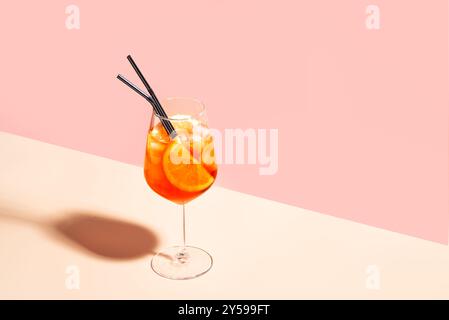 Aperol Spritz Cocktail im Glas mit orangefarbenen Scheiben auf rosa pfirsichfarbenem Hintergrund, Kopierraum, trendiges hartes Licht. Köstliches Sommergetränk Aperol Spritz Aper Stockfoto