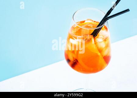 Aperol Spritz Cocktail im Glas mit orangefarbenen Scheiben auf hellblauem Hintergrund, Kopierraum, trendiges hartes Licht. Köstliches Sommergetränk Aperol Spritz Aper Stockfoto