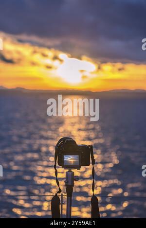 Farbenfrohes Bild mit einer DSLR-Kamera auf einem Stativ, das im Live View-Modus einen wunderschönen Sonnenuntergang über dem Wasser aufnimmt Stockfoto