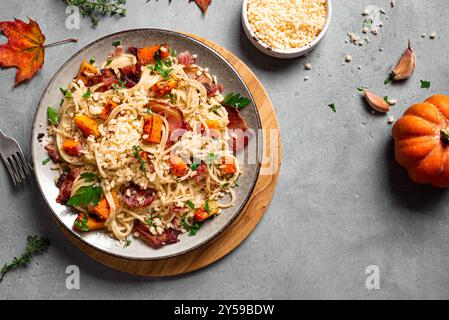 Kürbis-Speck-Pasta mit geriebenem Parmesankäse. Hausgemachte Spaghetti-Kürbisnudeln auf Betonhintergrund, Kopierraum. Saisonales Herbstessen. Pumpki Stockfoto