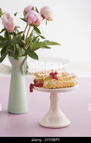 Eclairs mit buttercream Füllung auf eine rosa Kuchen stand Stockfoto