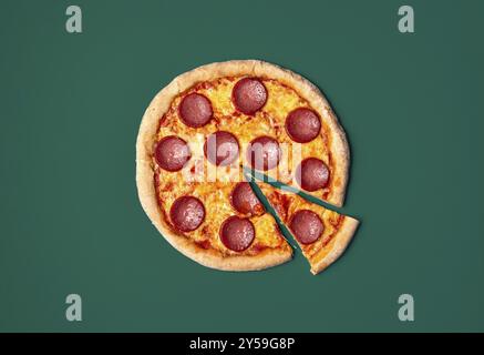 Blick von oben mit einer frisch gebackenen Pizza-Salami-Minimalist auf einem grünen Tisch Stockfoto