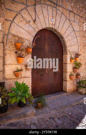 Rustikale Tür mit Blumentöpfen in einer malerischen Gasse auf Mallorca, horizontale Aufnahme, Valldemossa, mallorca spanien Stockfoto