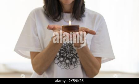 Nahaufnahme der Hände einer Frau, die eine glühende Kerze hüllt Stockfoto