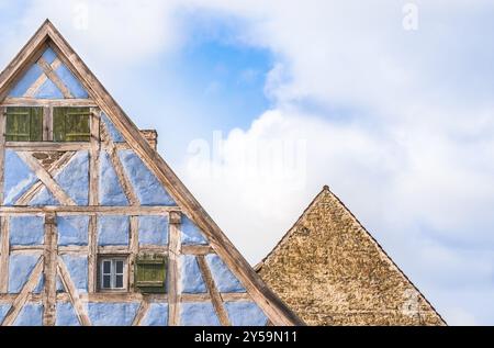 Architektonische Details von zwei Lofts aus mittelalterlichen deutschen Häusern, eines mit blauen Fachwerkwänden, Holzläden und eines mit Steinmauer Stockfoto