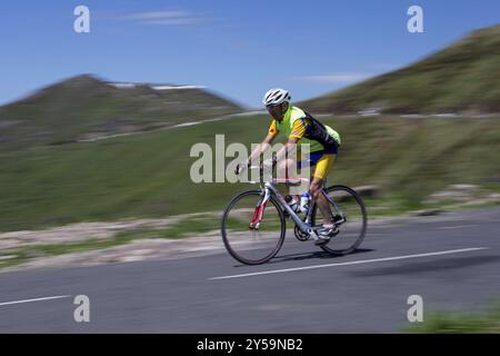Seitenansicht eines Radfahrers, der in den Bergen vorbeizieht Stockfoto