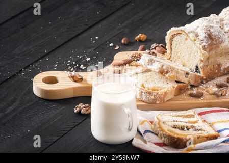 Herzhafter, hausgemachter Kuchen, gefüllt mit Mohn und gerösteten Walnüssen und Mandeln, und eine Tasse frische Milch auf einem Vintage-Holztisch Stockfoto
