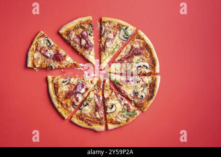 Pizza Prosciutto in acht Scheiben auf einem roten Tisch geschnitten. Hausgemachte leckere Pizza. Italienische Pizza mit frischen Zutaten, Prosciutto, Rucola, Mozzarella und c Stockfoto