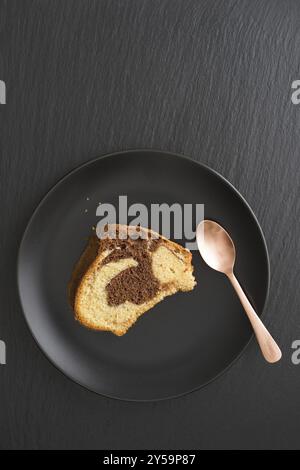 Ein Stück Marmorkuchen auf einem Teller auf Schwarz Stockfoto