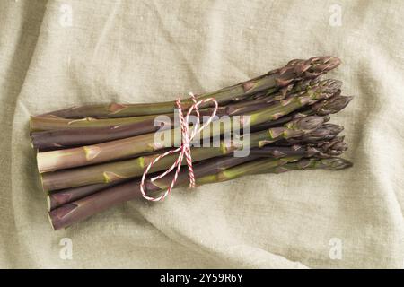 Ein Haufen lila Spargel auf Holztisch mit Leinentuch Stockfoto