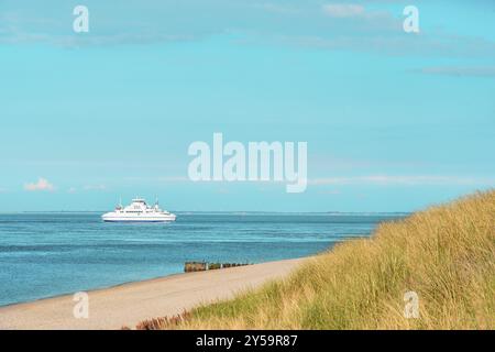 Sommerlandschaft mit Marramgras-Dünen und einem Boot, das in der Nordsee navigiert. Landschaft an einem sonnigen Tag auf Sylt, Deutschland, Europa Stockfoto