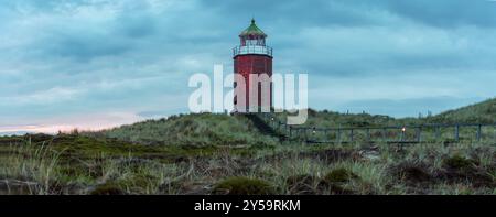 Sonnenuntergangspanorama auf Sylt Island mit einem roten Leuchtturm auf den Hügeln von Marram Grass. Abendlandschaft auf Sylt Islan, in der Nordsee, auf einem Klo Stockfoto