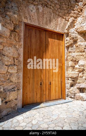 Antike Doppeltüren aus Holz in einer rustikalen Steinmauer, Mallorca, vertikaler Shot, Valldemossa, mallorca, Spanien Stockfoto