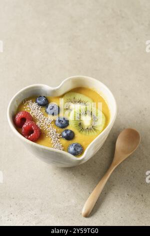 Peach smoothie Schüssel mit Blaubeeren, Kiwi, weiße Chia Samen und Himbeeren in Herzform Schüssel Stockfoto