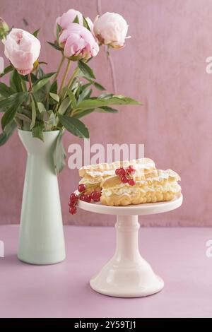 Eclairs mit buttercream Füllung auf eine rosa Kuchen stand Stockfoto