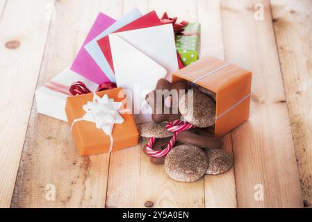 Lebkuchen in einer Geschenkbox in der Nähe von einem Stapel von Geschenken und bunten Umschläge Stockfoto