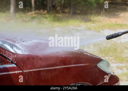 Das Auto wird mit einem unter Druck stehenden Wasserstrahl draußen vom Besitzer selbst gewaschen Stockfoto