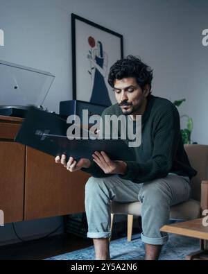 Junger, cool aussehender Hipster-Mann in der Wohnung, der Musik auf Schallplatten hört Stockfoto
