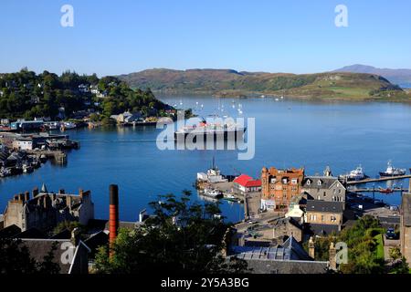 Oban, Schottland, Großbritannien. September 2024. Herrliches warmes und sonniges Wetter in Oban und an der Westküste mit Blick auf die Stadt und den Hafen und Blick auf die Berge von Mull. Die sonnigen Bedingungen werden voraussichtlich über das Wochenende andauern. Caledonian MacBrayne Fähre „Isle of Mull“, Abfahrt nach Craignure auf der Isle of Mull. Blick vom McCaig's Tower. Quelle: Craig Brown/Alamy Live News Stockfoto