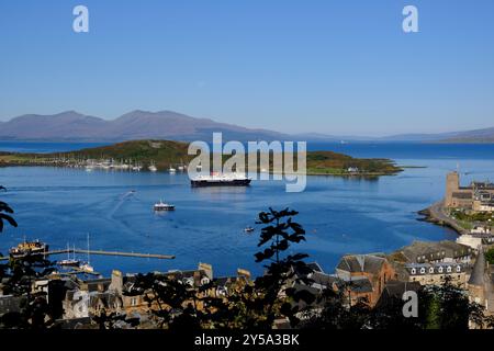 Oban, Schottland, Großbritannien. September 2024. Herrliches warmes und sonniges Wetter in Oban und an der Westküste mit Blick auf die Stadt und den Hafen und Blick auf die Berge von Mull. Die sonnigen Bedingungen werden voraussichtlich über das Wochenende andauern. Caledonian MacBrayne Fähre „Isle of Mull“, Abfahrt nach Craignure auf der Isle of Mull. Blick vom McCaig's Tower. Quelle: Craig Brown/Alamy Live News Stockfoto