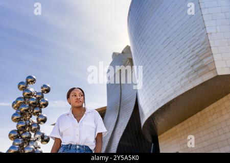 Eine junge Frau steht vor dem guggenheim Museum bilbao, mit einem selbstbewussten und stilvollen Auftreten Stockfoto