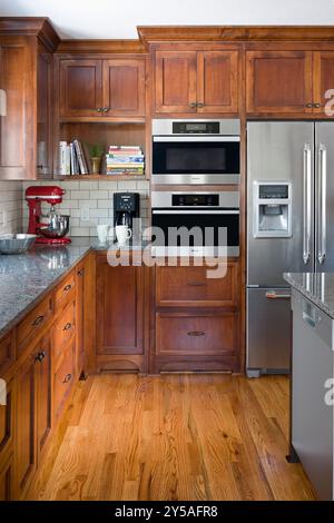 Ecke der Küche mit Kirschschschränken mit Geräten und Wandöfen Stockfoto