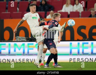 Augsburg, Deutschland. September 2024. Jeffrey Gouweleeuw (L) aus Augsburg streitet mit Jonathan Michael Burkardt aus Mainz während des ersten Bundesliga-Fußballspiels zwischen dem FC Augsburg und dem FSV Mainz 05 in Augsburg, Deutschland, 20. September 2024. Quelle: Philippe Ruiz/Xinhua/Alamy Live News Stockfoto