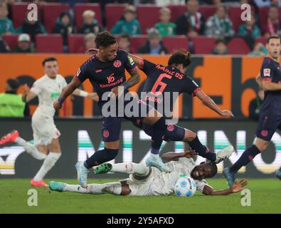 Augsburg, Deutschland. September 2024. Samuel Emmanuel Essende Mbongu (unten) aus Augsburg fällt während des Fußballspiels der ersten Bundesliga zwischen dem FC Augsburg und dem FSV Mainz 05 in Augsburg, Deutschland, 20. September 2024. Quelle: Philippe Ruiz/Xinhua/Alamy Live News Stockfoto