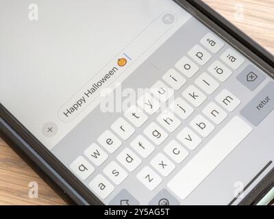Ein Nahfoto eines Smartphone-Bildschirms mit einer Halloween-Begrüßung, komplett mit einem bezaubernden Kürbis-Emoji. Stockfoto