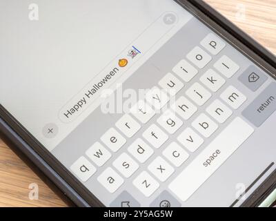 Ein Nahfoto eines Smartphone-Bildschirms mit einer Halloween-Begrüßung, komplett mit einem gruseligen Geist und einem verspielten Kürbis-Emoji. Stockfoto