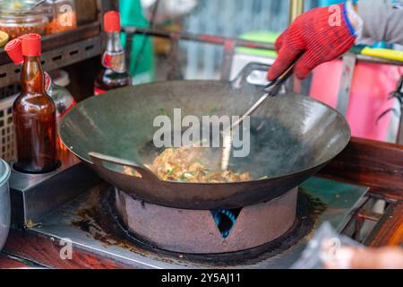 Verkaufsautomat gebratene, klebrige Reiskuchen in der Pfanne genauso wie thai gebratene Nudeln „Pad Thai“ auf einem Straßenmarkt in der Altstadt Thailands. Alte Foo Stockfoto