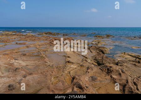 Eine felsige Küstenlandschaft mit flachen Gezeitenbecken unter einem klaren blauen Himmel. Das ruhige Meer trifft auf die zerklüftete Küste und schafft eine friedliche natürliche Landschaft Stockfoto