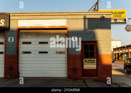Autogarage an einer belebten Straße. Schatten aus der goldenen Stunde erhellen das Straßenfoto. Stockfoto