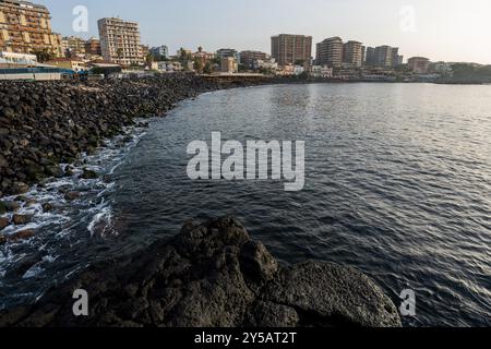 Catania, Italien - 20. Mai 2024: Die felsigen Küsten von Catania: Eine Mischung aus urbaner Skyline und ruhigem Wasser. Stockfoto