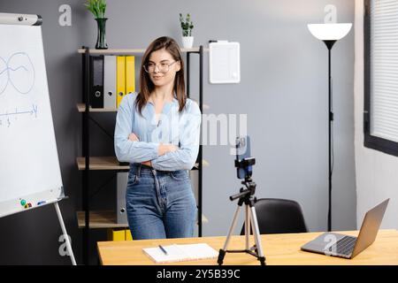 Junge Frau Mentorin nimmt Präsentationen auf, Webinar über Smartphone auf Stativ stehend, Lehrer Coach erklärt, hält Online-Unterricht, mit Telefon-Webc Stockfoto