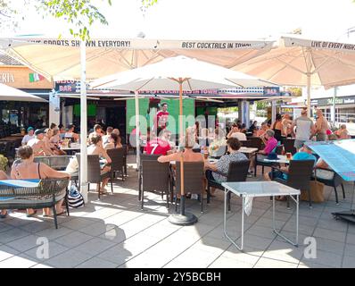 Palmanova, Spanien; 10. august 2024: Terrasse einer Bar mit englischen Touristen, die ein Fußballspiel beobachten, im mallorquinischen Ferienort Palmanova auf einem Su Stockfoto