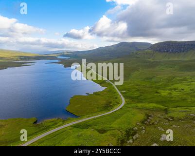 Die landschaftlich reizvolle Route an der Nordküste 500 schlängelt sich um einen See in den schottischen Highlands in der Nähe von Old man of Storr auf der Isle of Skye, Schottland Stockfoto