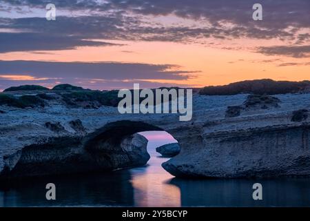 Arco di S'Archittu, ein 17 Meter hoher Felsbogen, das Ergebnis der Meereserosion einer alten Höhle, die sich im Kalkstein gebildet hat, bei Sonnenuntergang. Stockfoto