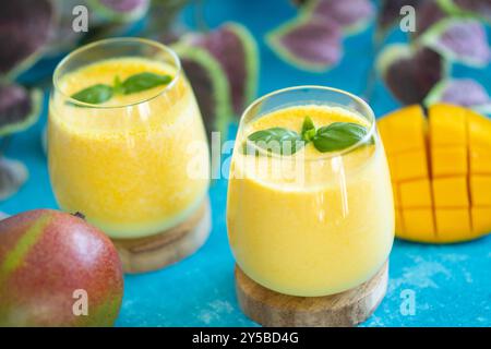 Frische Mangolassi in Gläsern auf blauem Hintergrund mit Kopierraum. Indischer gesunder detoxic ayurvedischer Kaltwasser mit Mango. Frische Lassi aus Yogur Stockfoto