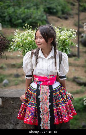 Das lokale Hmong-Mädchen verkauft Blumen entlang der Ha Giang Loop in den Bergen Nordvietnams Stockfoto