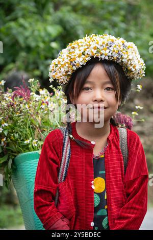 Das lokale Hmong-Mädchen verkauft Blumen entlang der Ha Giang Loop in den Bergen Nordvietnams Stockfoto