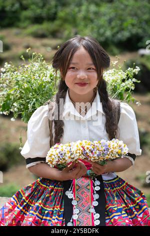 Das lokale Hmong-Mädchen verkauft Blumen entlang der Ha Giang Loop in den Bergen Nordvietnams Stockfoto