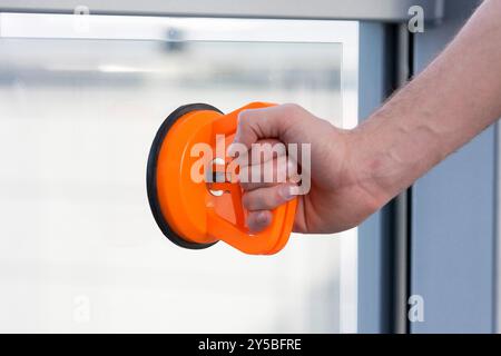 Fenster mit orangefarbenem Saugnapf halten in der Hand Stockfoto