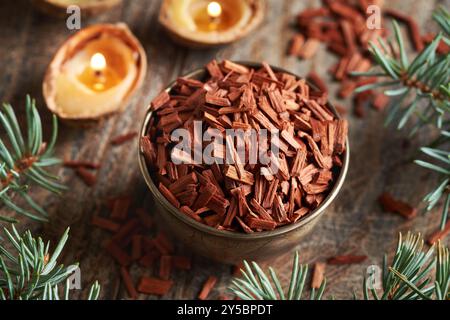 Rote Sandelholzchips in einer Schüssel mit Weihnachtskerzen und Fichtenzweigen auf einem Tisch Stockfoto