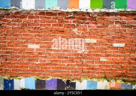 Alte Ziegelmauer mit bunten Elementen. Stockfoto