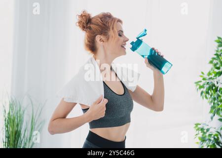 Foto einer sportlichen hübschen Frau, die Aktivkleidung trägt und körperliche Übungen von zu Hause aus im Wohnzimmer tätigt Stockfoto